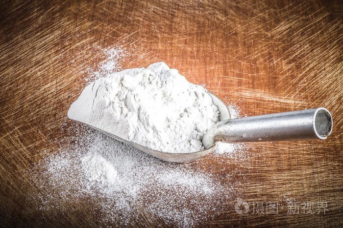 用白色小麦粉在一个旧的坚固的切割板上铲子吨
