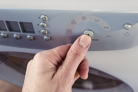 清洗机按钮拇指按下洗衣机控制面板上的按钮照片