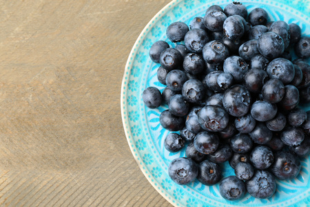 木制的桌子上的盘子上新鲜的蓝莓关闭