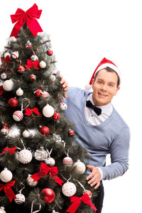 戴圣诞帽的男人在圣诞树后面