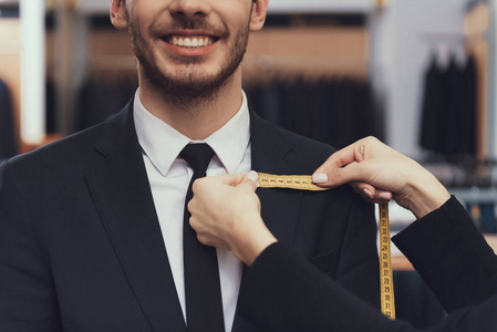 关门了裁缝用卷尺测量客户尺寸以适应量身定做的西装照片