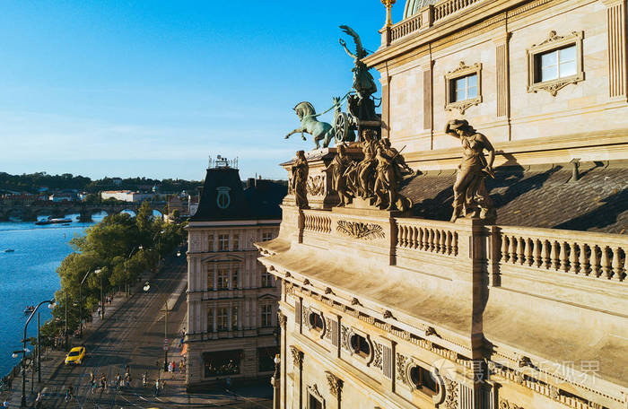 美丽的鸟瞰布拉格国家剧院沿河伏尔塔瓦河。日落时的壮观剧场观与屋顶上的马雕塑