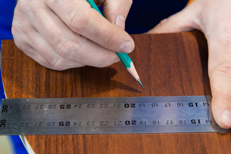 特写手在尺子上画一支铅笔, 上面有一个分标准模板, 用来剪下拼图和家具夹子旁边的家具细节。
