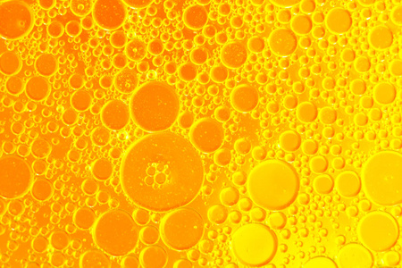 黄色漂浮油滴漂浮在水抽象的橘黄色背景照片
