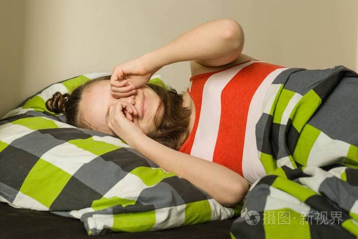十几岁的女孩醒来揉眼睛躺在床上的枕头上上面的景色