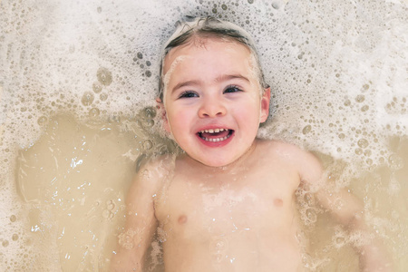 可爱的沐浴在头发上肥皂泡沫的婴孩女孩