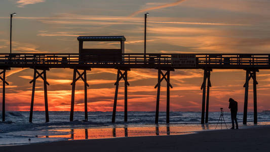 五颜六色的日落在海洋海岸与剪影的码头和相片
