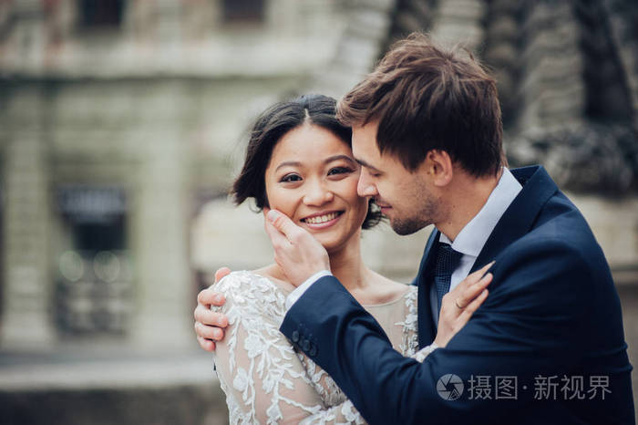 新郎温柔拥抱亚洲新娘白色礼服