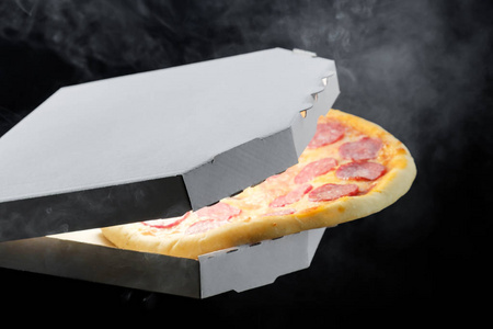 热香肠美味比萨在打开纸板箱, 融化奶酪蒸汽烟雾黑色背景