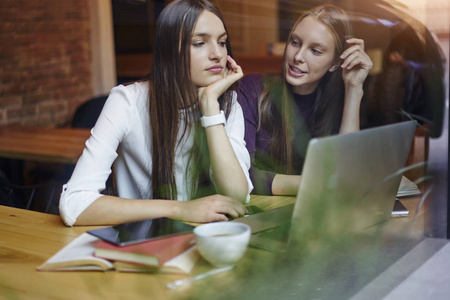 创意时髦的女孩在休息时, 坐在桌面上的笔记本电脑设备在大学内部。coworking 空间考试准备中的聪明青少年交流