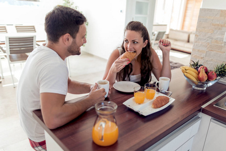 年轻幸福的情侣坐在现代公寓和一起吃早饭
