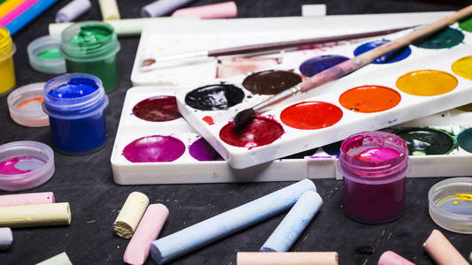 明亮的彩色的油漆，蜡笔，蜡笔，铅笔，刷上黑色的木背景。设置为艺术家。教育