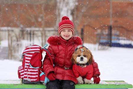 小女孩用公文包和狗在放学后的冬天散步