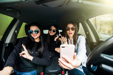 三个年轻开朗美女自拍照，微笑着坐在车里在一起