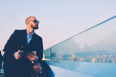 新媒体人有信心的商人在时尚的太阳镜和优雅的西装侧面看着一边, 同时