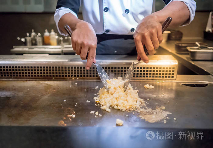 手的厨师烹饪大蒜炒米饭热平底锅在铜上