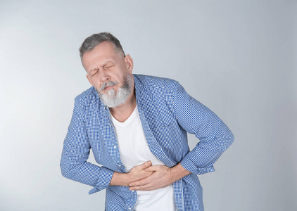 患有腹部疼痛的男子在光的背景下照片