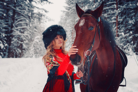 美丽的姑娘和英俊的种马，冬天在性质上的马的画像