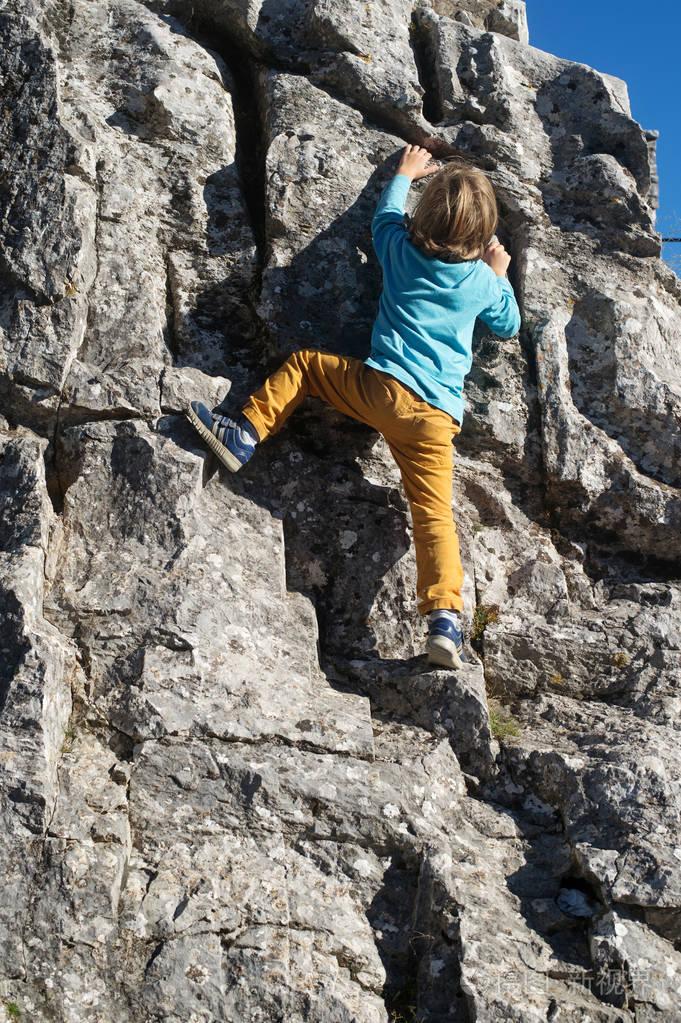 小男孩爬上岩石面对挑战对抗与成功理念
