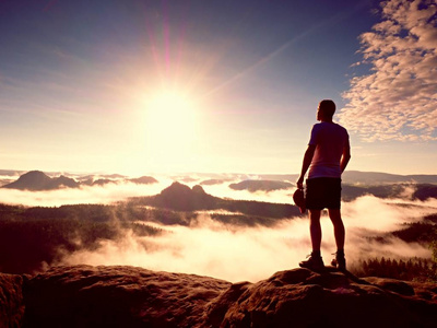 男人走岩石首脑会议到太阳美丽时刻的自然奇迹.老式的影响照片