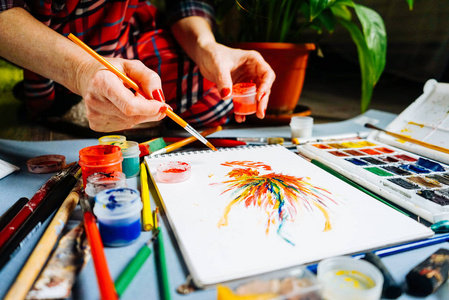 女画家用彩色水彩颜料在白纸上作画照片