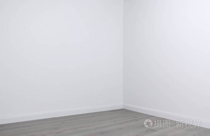 白色的墙壁和木地板在空房间的角落里