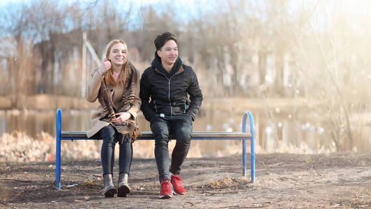 一对年轻的人在公园里相遇.恋人坐在照片