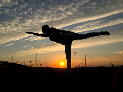 女人在日落时分在一条腿平衡