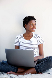 坐在地板上的年轻非洲裔美国妇女的肖像笔记本电脑