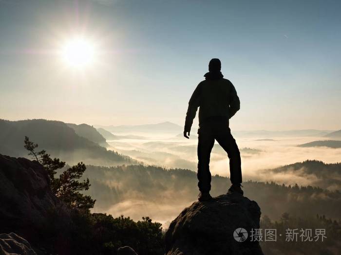 高高站在悬崖的人.徒步旅行者爬上岩石峰值和欣赏的景色