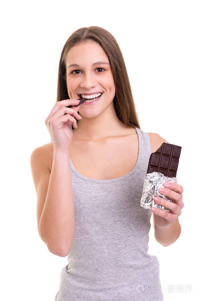 一个美丽的年轻女人吃一块巧克力片的白色背景隔离
