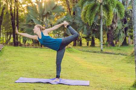 白天在热带公园练习瑜伽的年轻女子