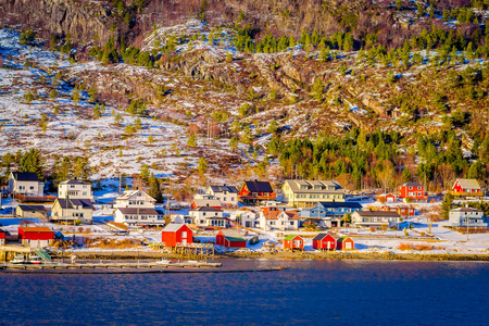 从挪威北部的 Hurtigruten 航程中长在海岸的木房子的冬天看法