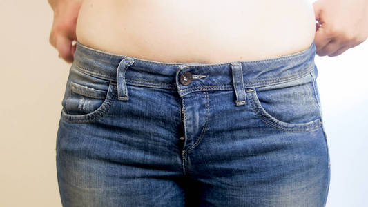 蓝色牛仔裤的年轻肥胖妇女特写图像