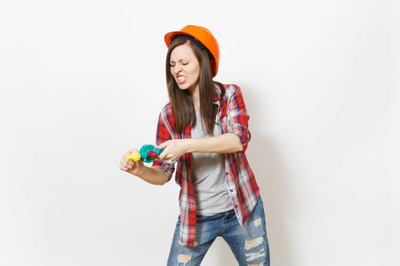 恼怒的疯狂的妇女在休闲衣服和保护性建筑橙色头盔手持玩具钻隔离在白色背景。设备, 翻新公寓房间的工具。修复主页概念