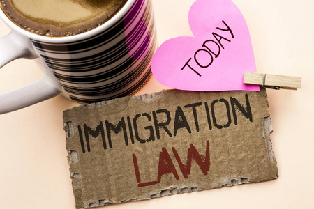 显示移民法的文本符号。概念照片国家条例为移民驱逐出境规则写在撕裂纸板片上的纯背景粉红色的心和咖啡杯
