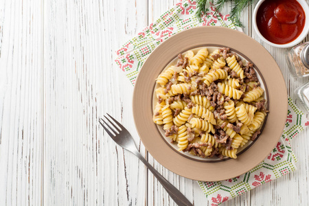 Fusilli 面食与碎肉和洋葱在海军风格的白色木桌。Makarony flotski, 俄罗斯菜