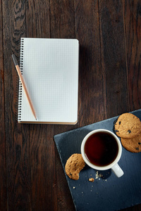 杯茶与饼干, 工作簿和铅笔在木质背景, 顶部视图