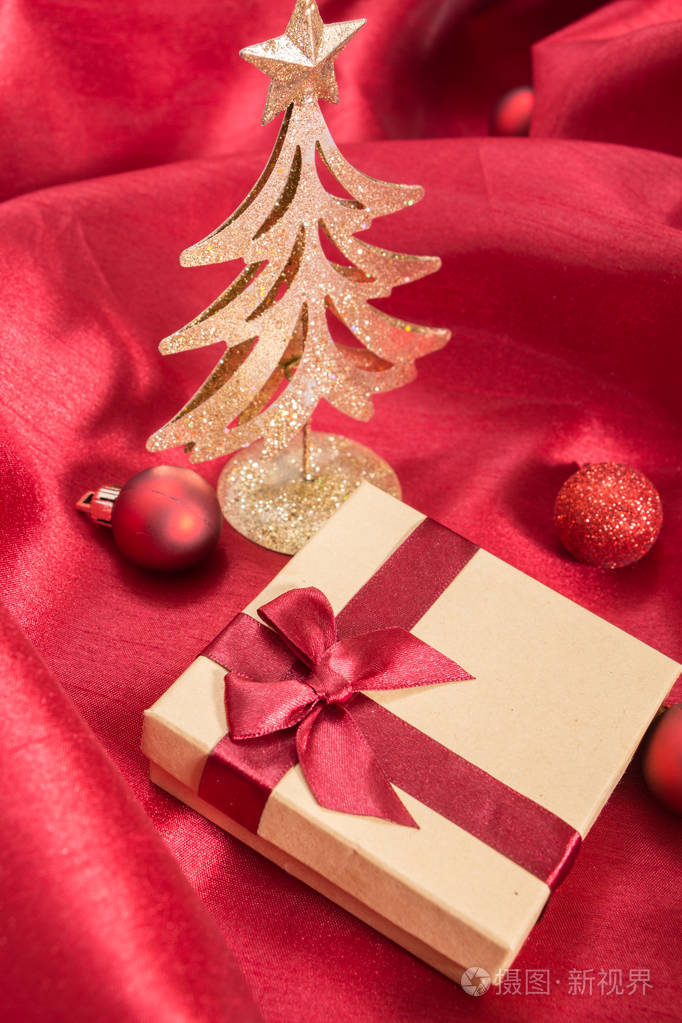 蝴蝶结圣诞饰品红色波浪缎织物上的礼品盒