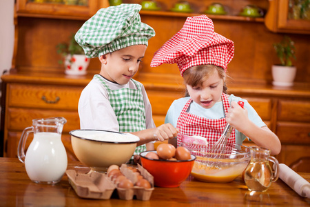 两个快乐的孩子们准备在厨房里的饼干鸡蛋