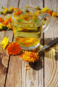 从花的万寿菊在透明的玻璃杯子里的茶。金盏花的药用花