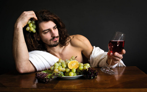 长长的卷发杯红色的饮料和一盘葡萄同桌一个帅哥的肖像照片