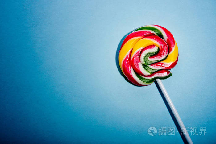 彩色螺旋棒糖糖在棍子上在蓝色背景上