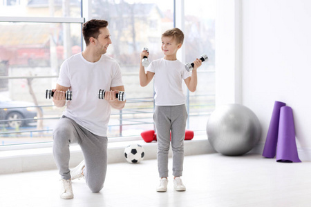 爸爸和儿子在健身房训练哑铃