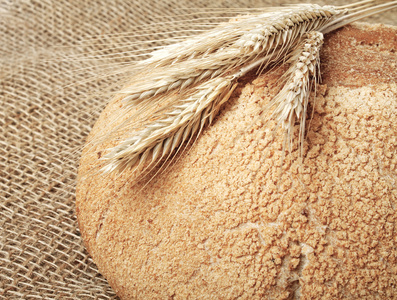 面包和小麦秸秆粗麻布背景上图片