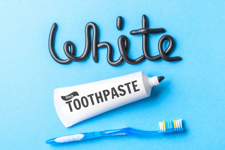 炭黑牙膏, 白牙。黑色牙膏, 管子和牙刷在蓝色背景下的字白色