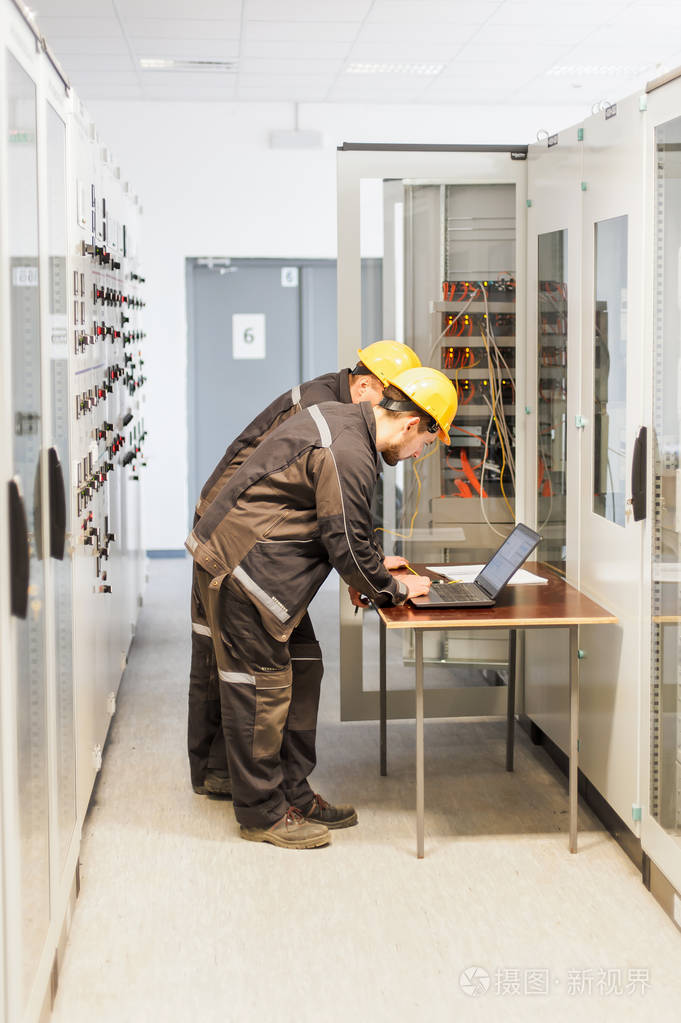 两个维修工程师与l一起检查继电保护系统