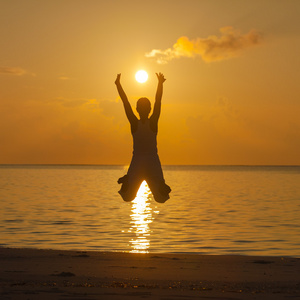 快乐的年轻女人在海滩上跳跃
