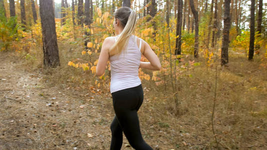 秋天森林的年轻金发女子马尾辫慢跑