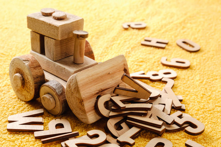 木制字母与玩具。黄色背景下的教育理念